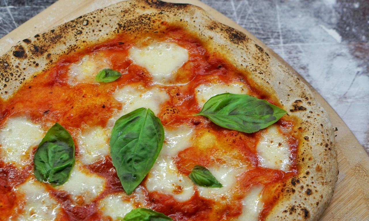 a closeup of a southern Italian pizza neapolitana, garnished with whole fresh basil leaves