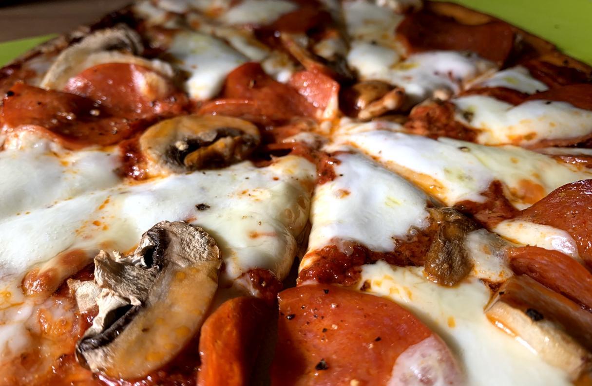 closeup of a tortilla pizza with tomato purée pizza sauce, mozzarella, pepperoni and mushrooms