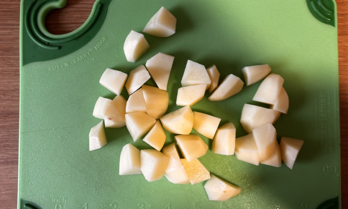 raw potato chunks, peeled, on a green chopping board