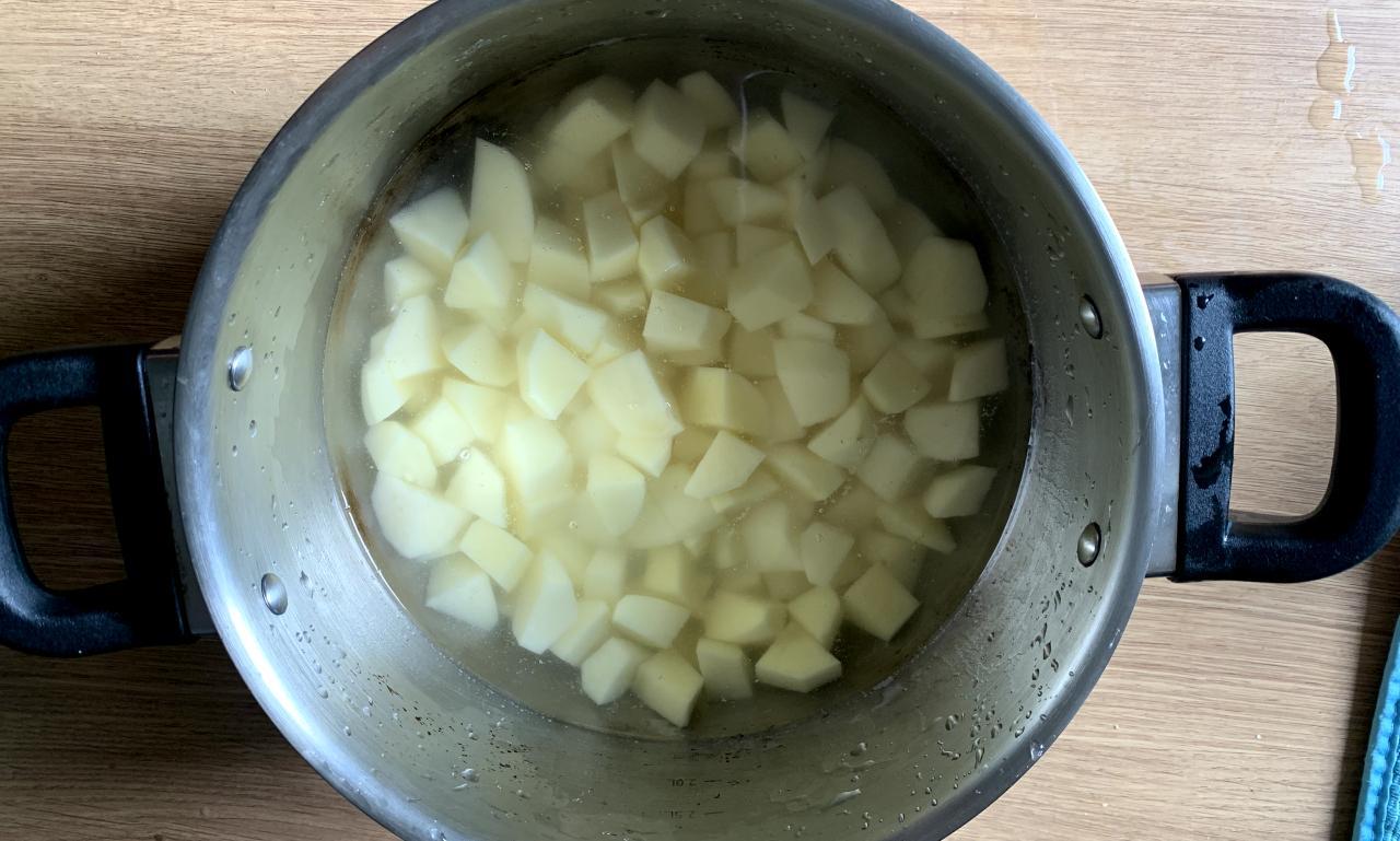 cubes of potato soaking in a pot of cold water