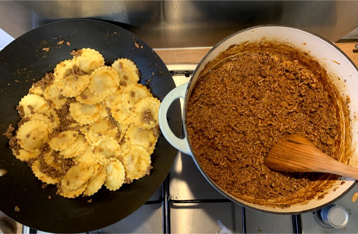 Two pots on a stove, one with ragu and pasta and one full of Ragù alla Ferrarese