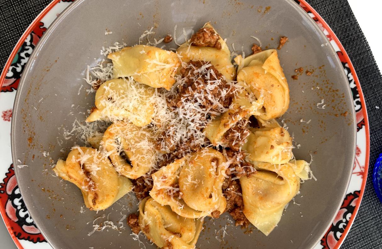 a small plate of cappellacci with Ferrarese ragu and parmigiano reggiano