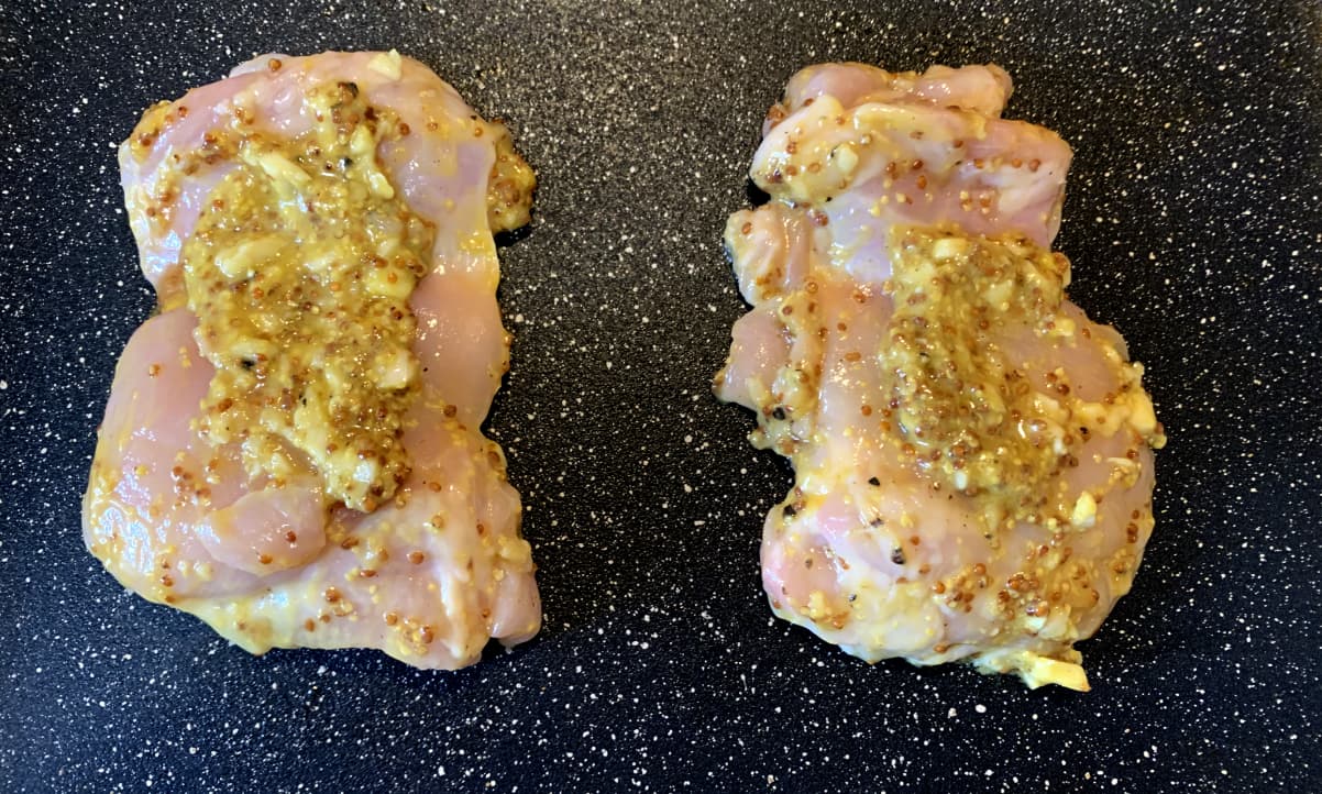 chicken thighs with wholegrain mustard sauce sitting on a baking tray