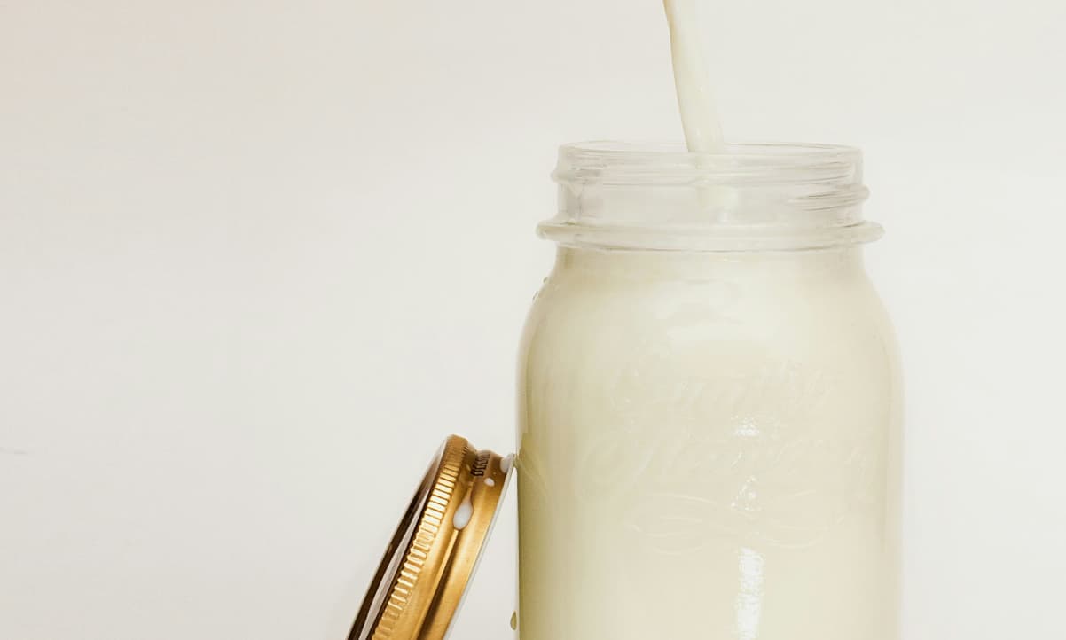 a transparent bottle with milk being poured inside