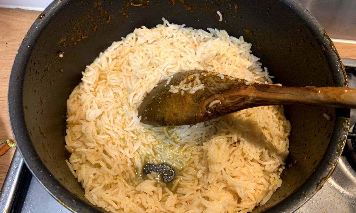 microwave rice being cooked in a pan, stirred with a wooden spoon