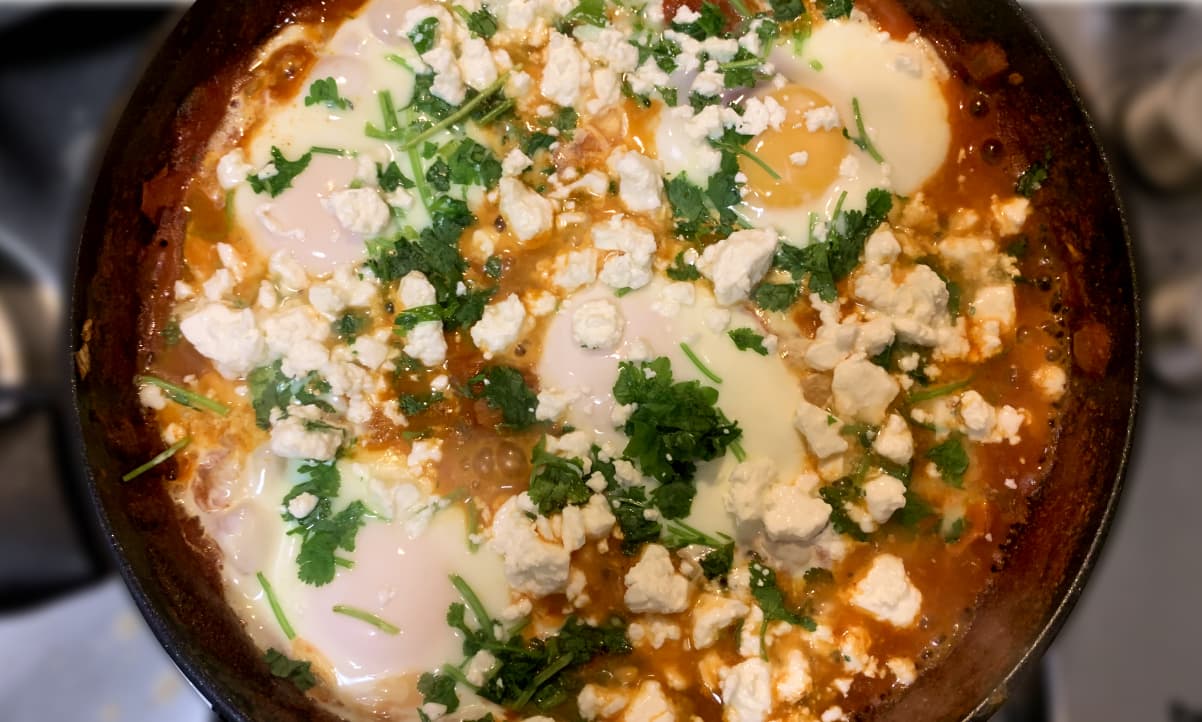 shakshouka garnished with corriander and feta in a pot