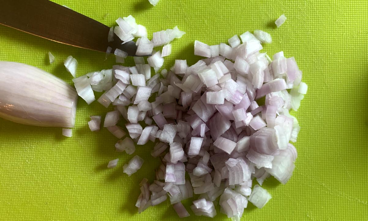 finely diced shallots on a green chopping board