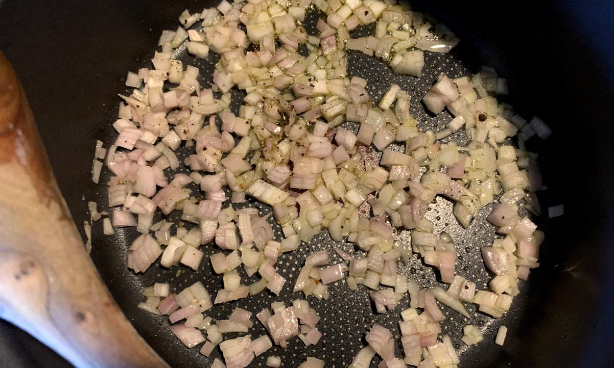 shallots frying in a black pan