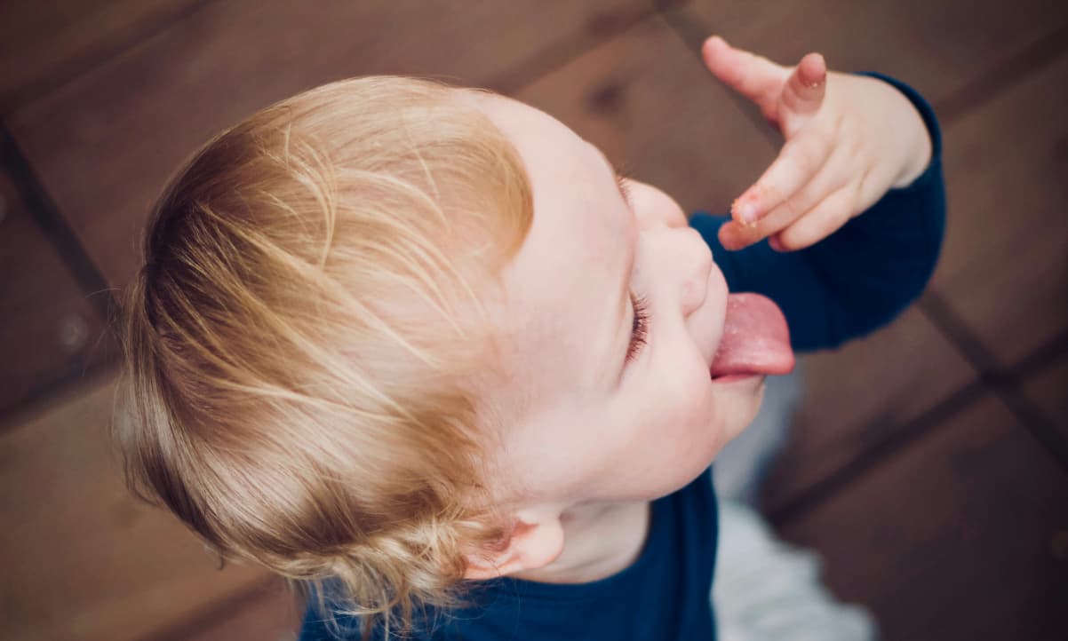 a happy baby making a jeering hand gesture