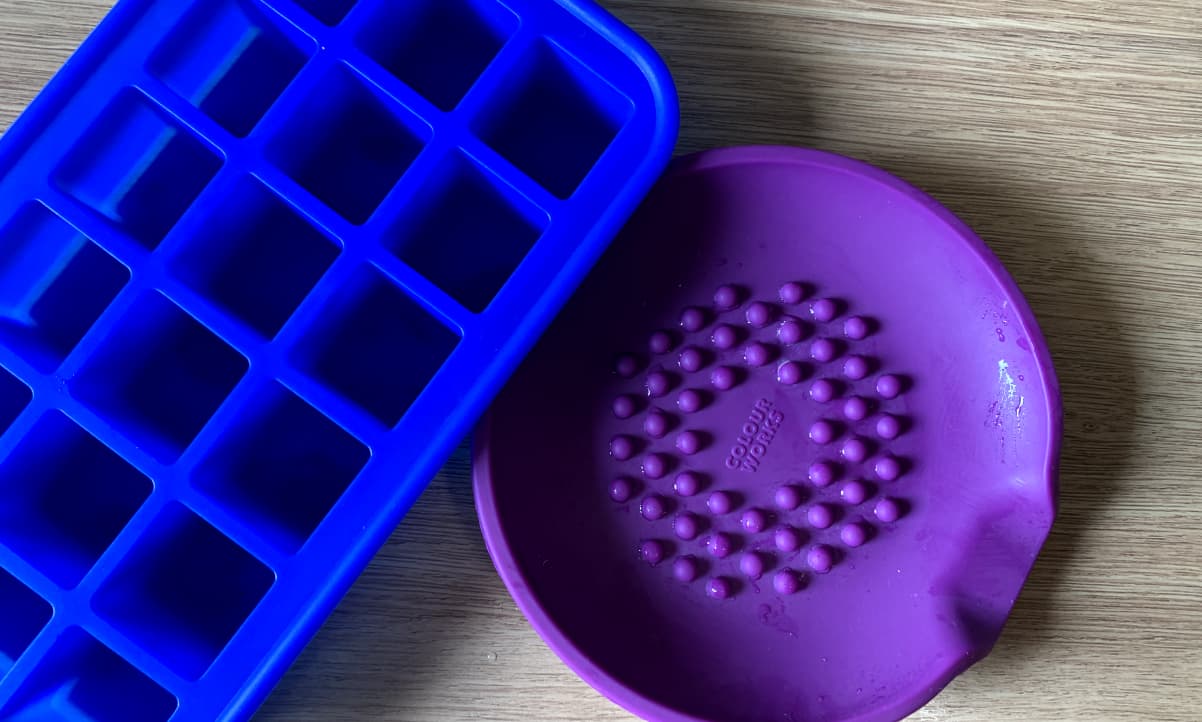 a blue silicone ice cube tray, and a purple silicone spoon rest