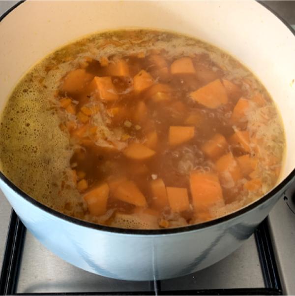 carrot and sweet potato soup cooking in a large pot on the hob