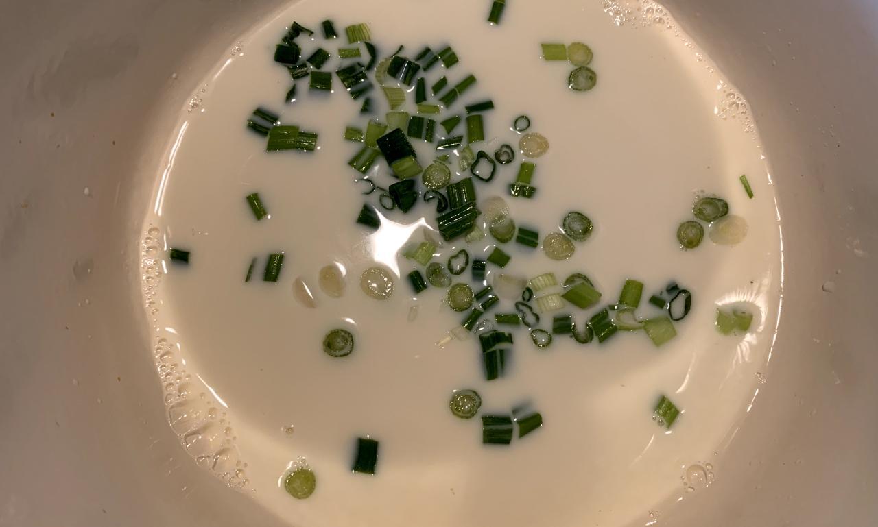 chopped spring onion sitting in a pot of milk