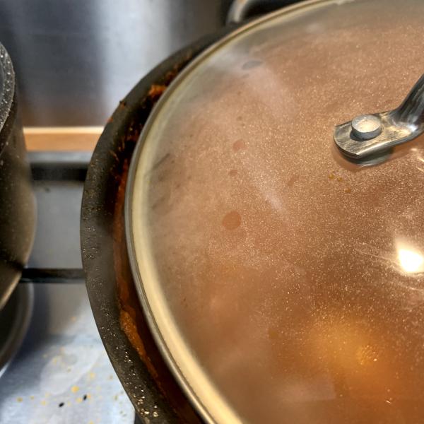 a closeup of a pan lid on a cooking pot, slightly ajar