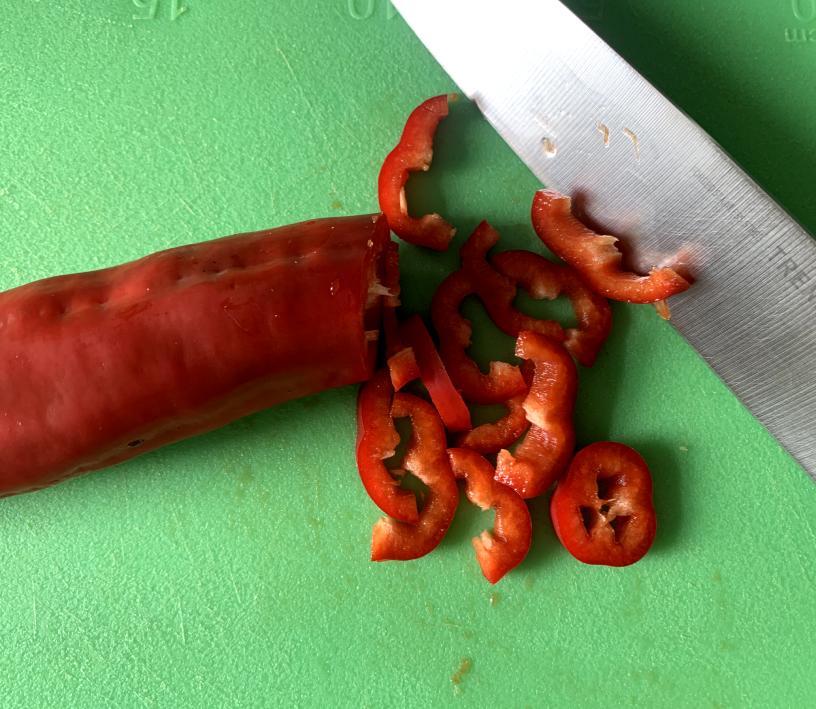 sweet red pepper being sliced with a large knife