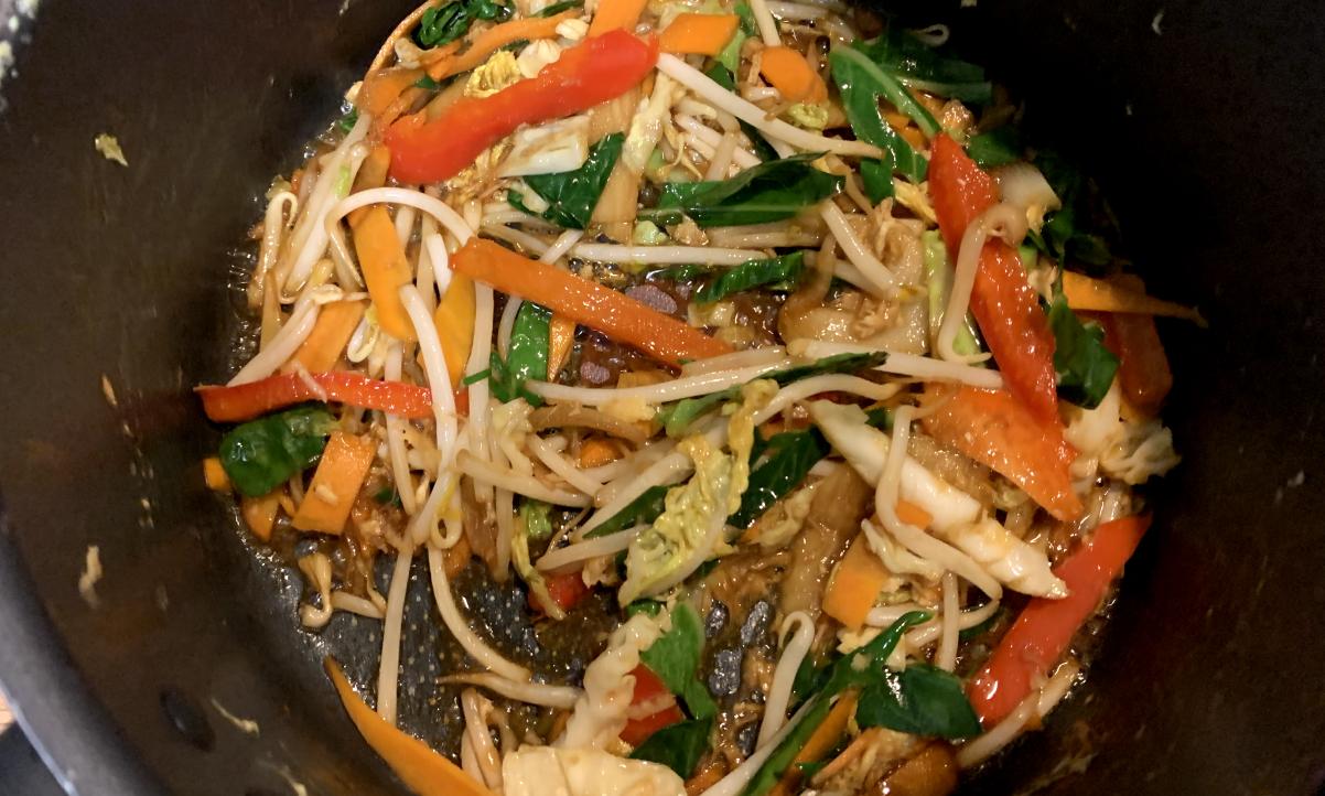 Sliced assorted vegetables and bean sprouts frying in a pan