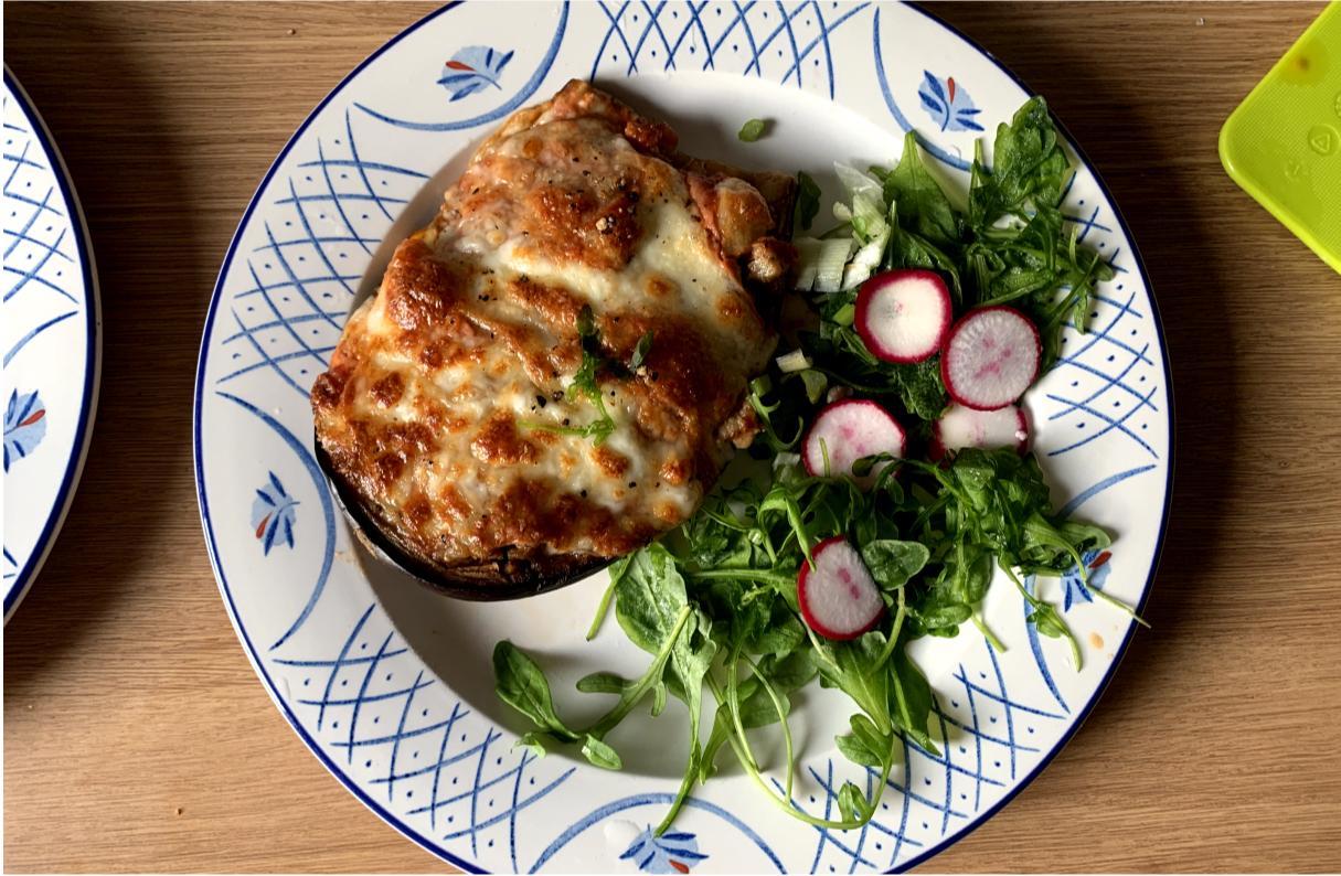 aubergine stuffed with ragu, topped with melted mozzarella, with rocket and radish slices on the side