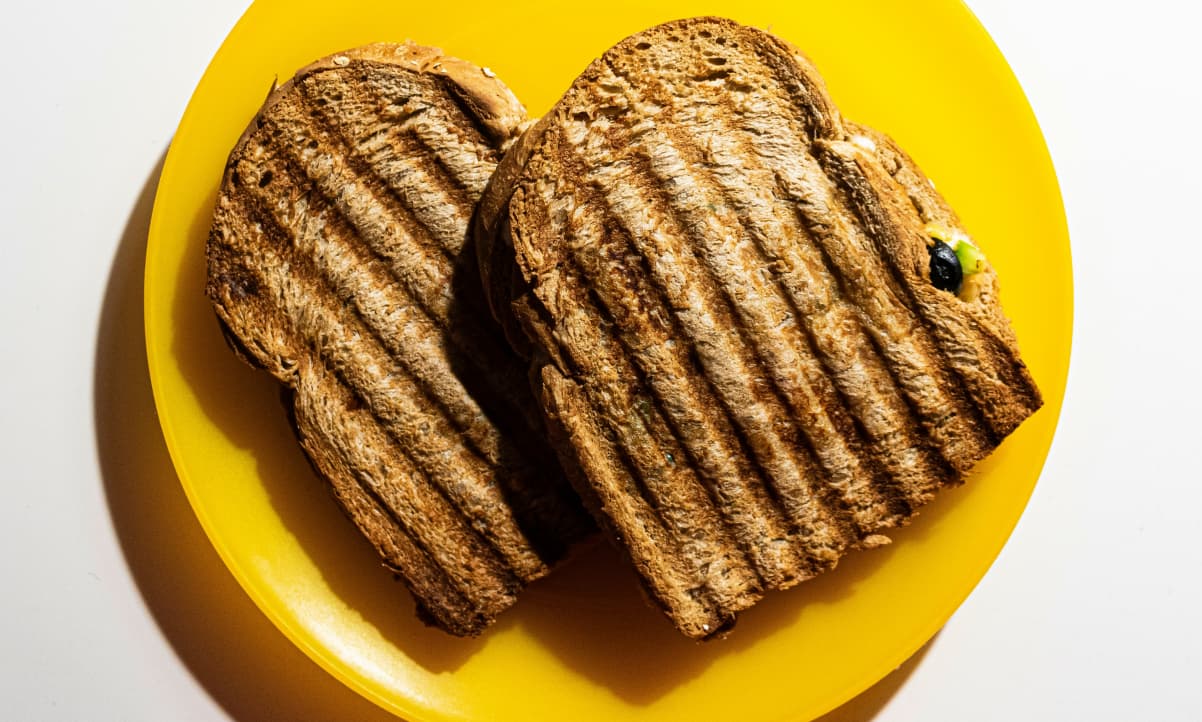 two toasted cheese sandwiches on a yellow plastic plate