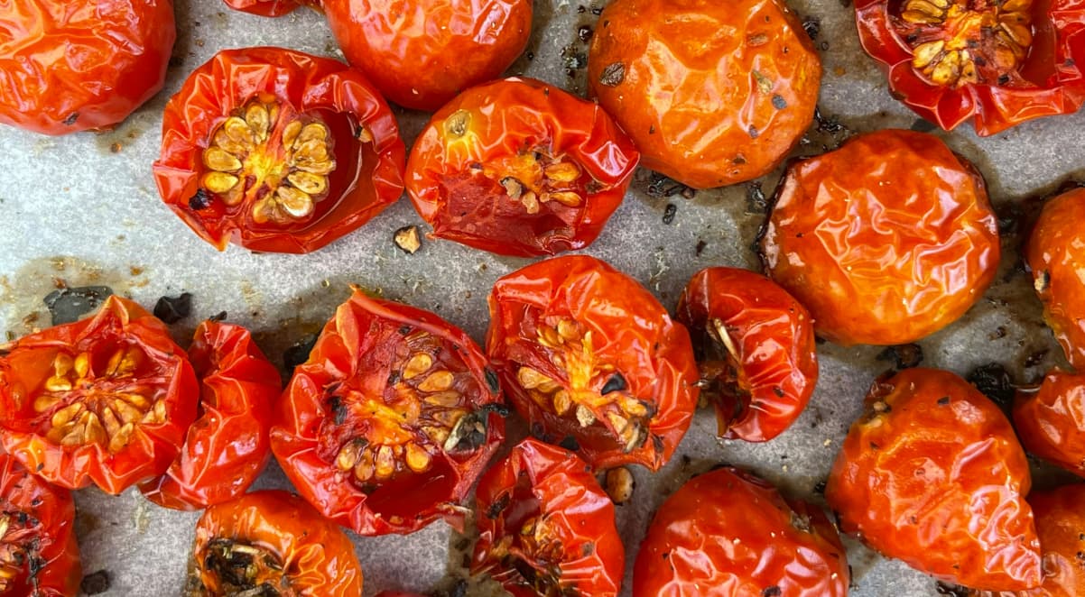 bright red, cooked cherry tomatoes on baking paper, seasoned with oil and black pepper