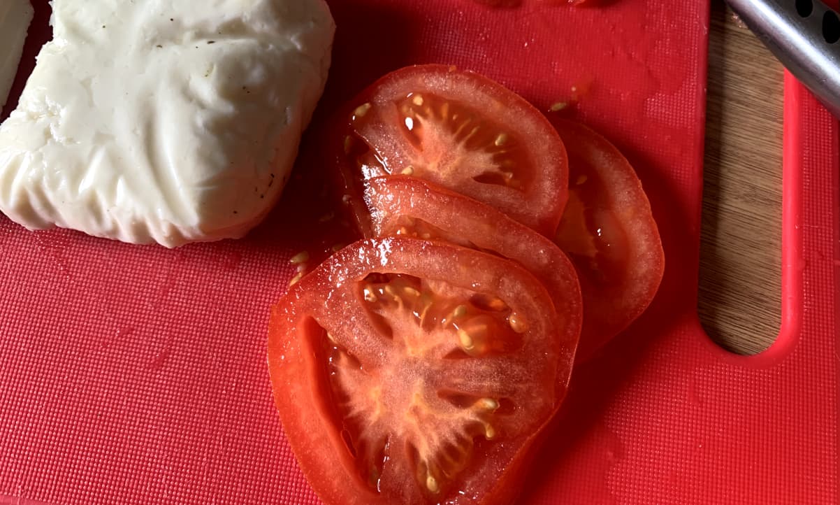 slices of fresh tomato on a red chopping board