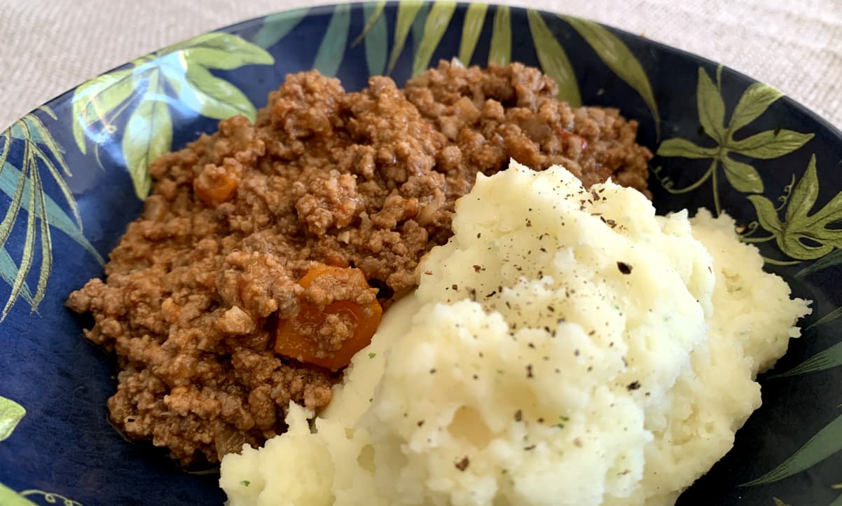 mince and tatties in a blue and green bowl, seasoned with black pepper