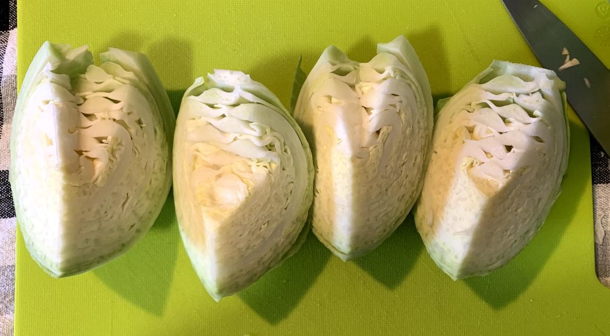 a white cabbage, quartered, with the inner stem removed