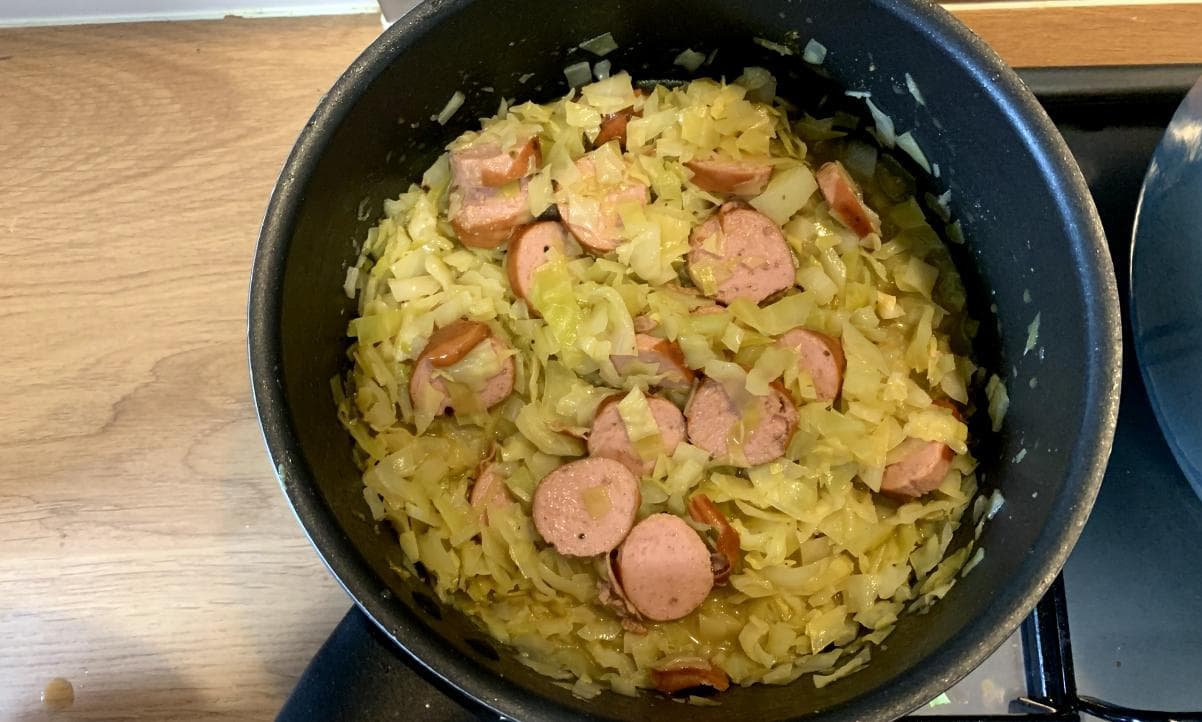 fennel cabbage and slices of smoked sausage in a cooking pot