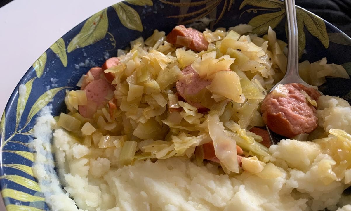 cabbage and smoked sausage served with mashed potatoes in a bowl